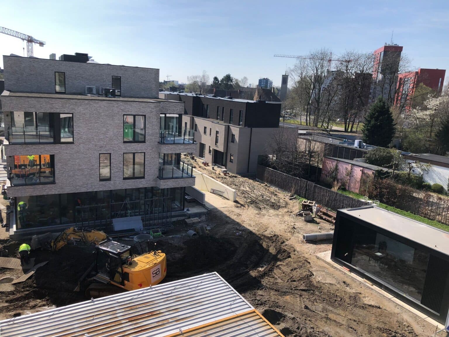 Crawler excavator at work between the new Maple Garden buildings in Ghent during the sewer works