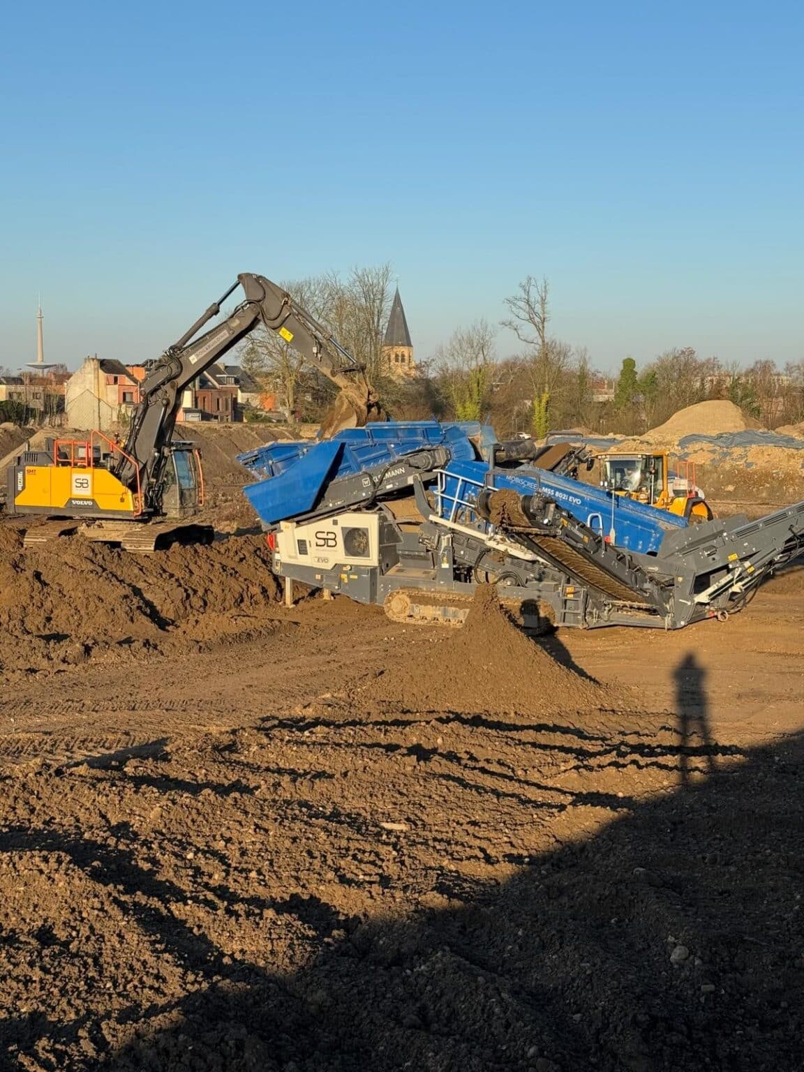 Zeefinstallatie en graafmachines zeven vervuilde grond op de Ragheno-site in Mechelen